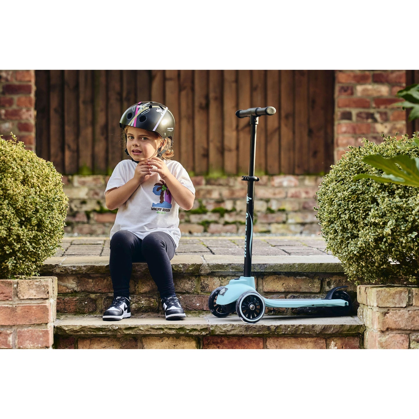 child sitting on steps next to Ride-Ezy Kick & Go Scooter - Kingfisher