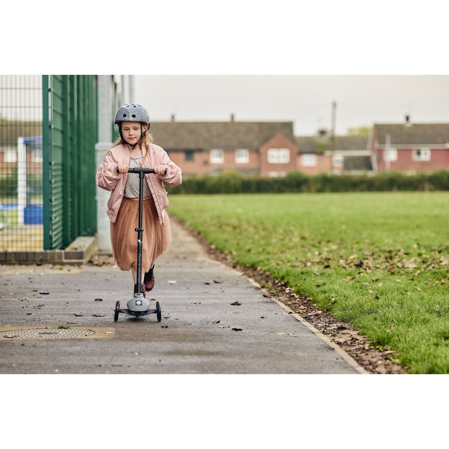 girl riding Ride-Ezy Kick Scooter - Thunder Clouds on pathway near field