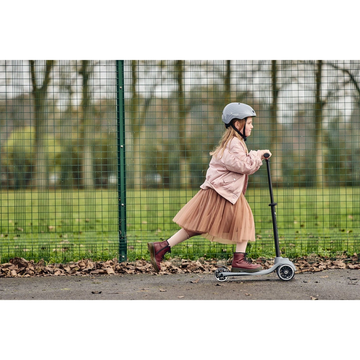 girl riding Ride-Ezy Kick Scooter - Thunder Clouds in front of metal fence