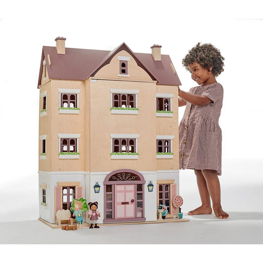 smiling child standing next to Tender Leaf Fantail Hall Deluxe Wooden Dolls House