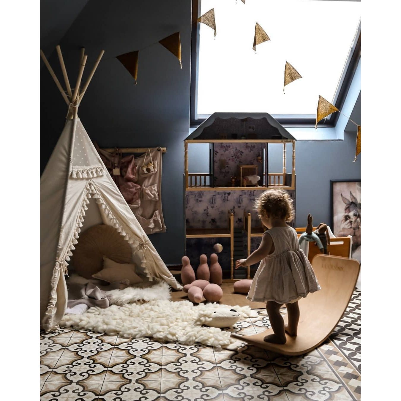 little girl standing on balance board in playroom with MINICAMP Boho Kids Teepee With Tassels