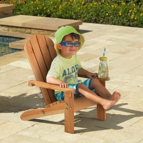 boy sitting in KidKraft Adirondack Chair - Honey by swimming pool