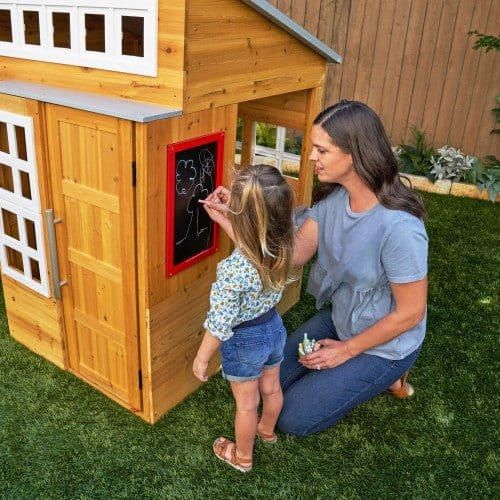 woman and child next to KidKraft Modern Outdoor Playhouse and writing on chalkboard