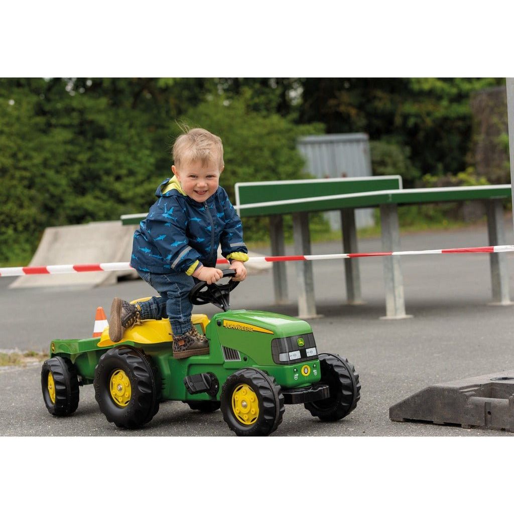 smiling boy climbing onto Rolly Toys John Deere Tractor & Trailer