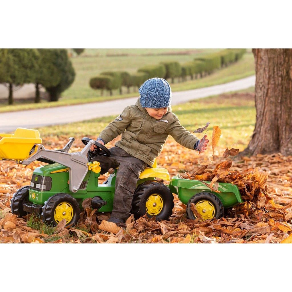 boy riding Rolly Toys John Deere Tractor & Frontloader & Trailer in autumn leaves