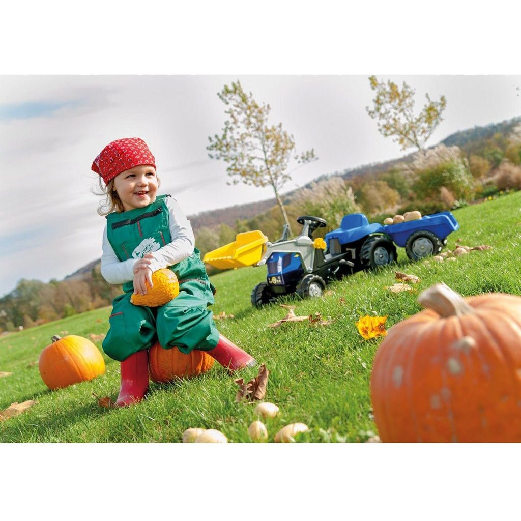 girl sitting on oumpkin in field with Rolly Toys New Holland T7040 Tractor with Frontloader & Trailer