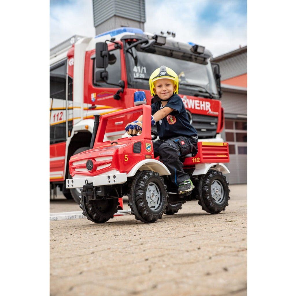 boy in firefighter costumer sitting in Rolly Toys Mercedes Unimog Fire & Rescue Truck