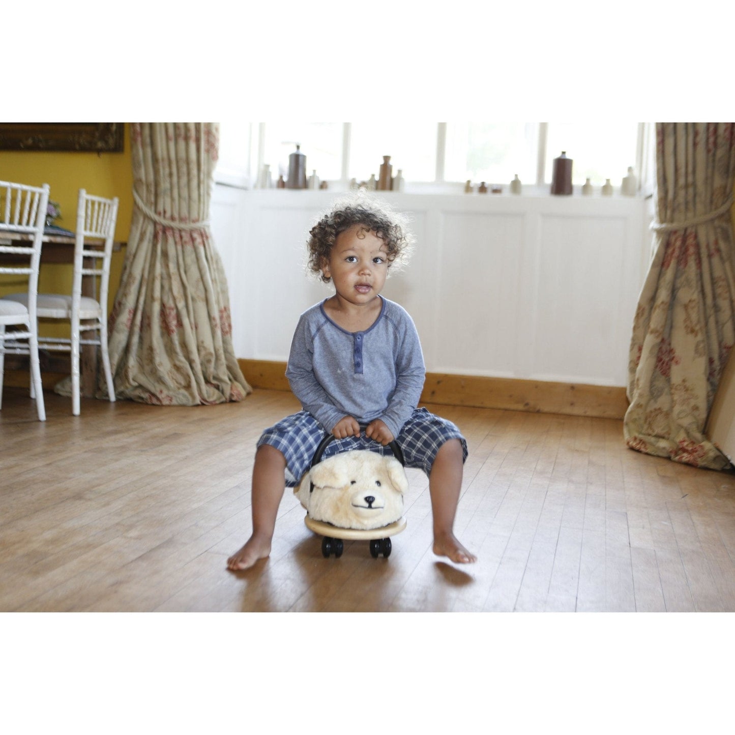 little girl riding Wheelybug Plush Ride On - Dog