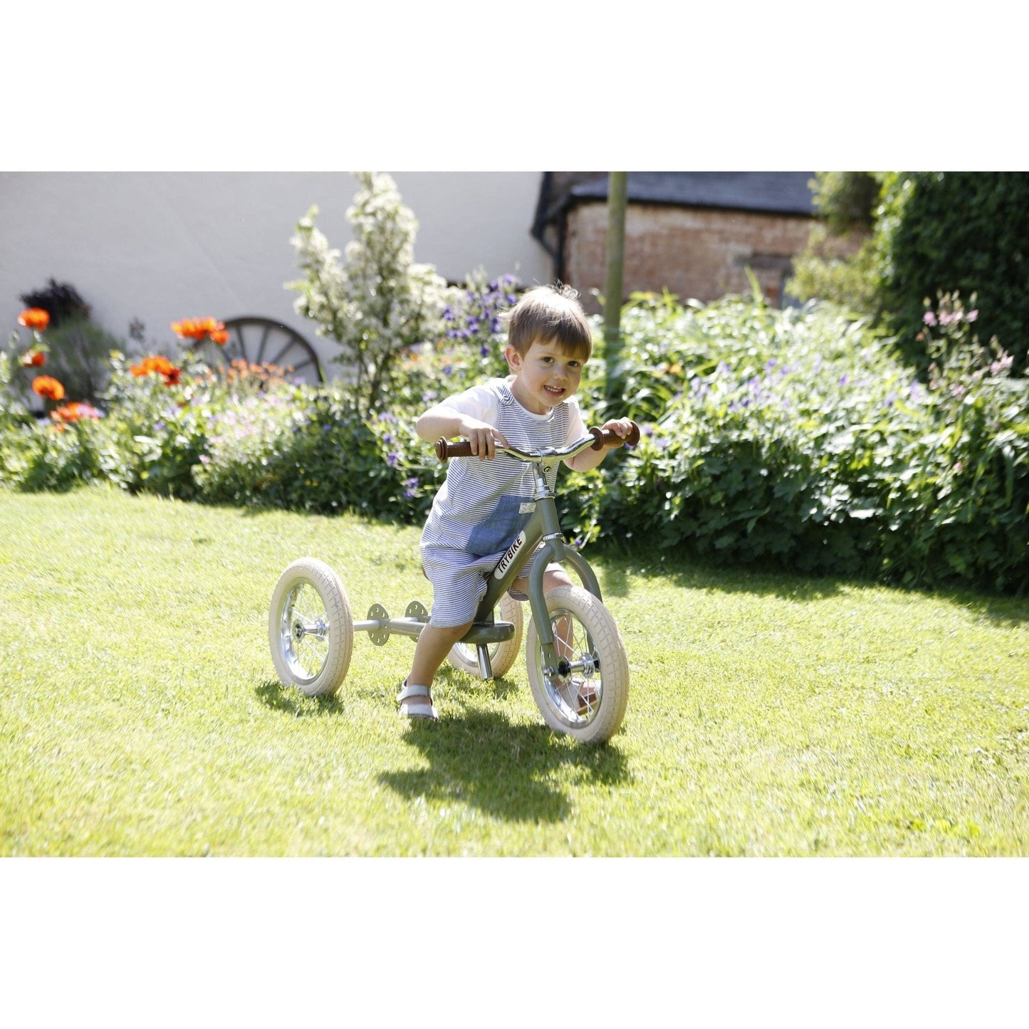 smiling boy riding TryBike - Steel 2 in 1 Balance Trike Bike - Vintage Green in garden
