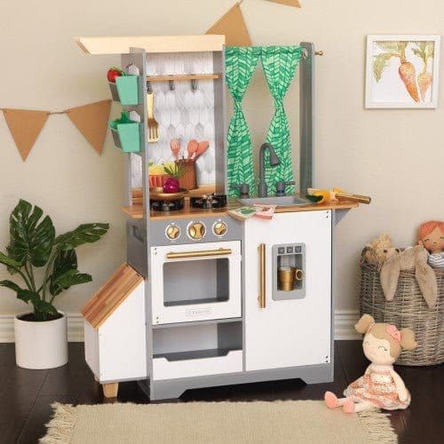 doll on floor in front of Kidkraft Terrace Garden Play Kitchen