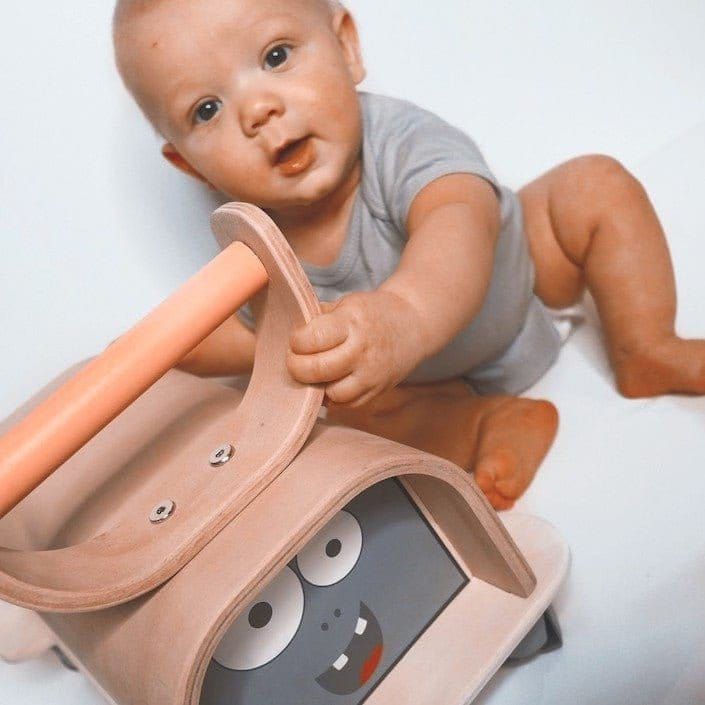 baby holding Mama Toyz Wooden Monster Ride-On Age 12 Months +
