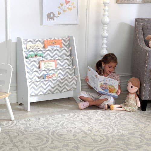 gfirl reading book with dolly in front of KidKraft Sling Bookshelf - Gray & White in playroom