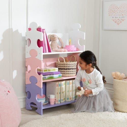 girl sitting in front of Kidkraft Puzzle Bookshelf - Pastel