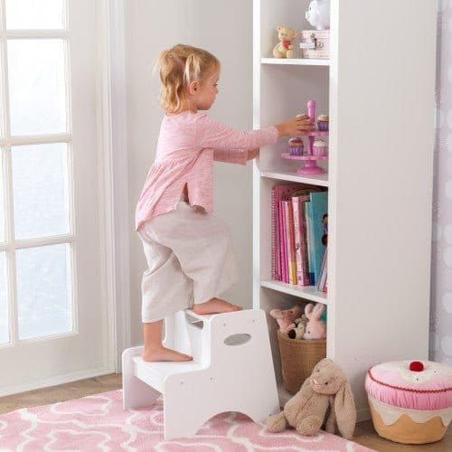 girl using KidKraft Two-Step Stool - White to reach shelf