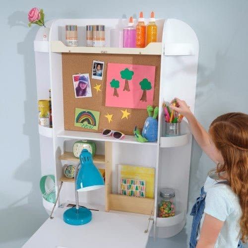 girl getting pen from shelf of KidKraft Arches Floating Wall Desk & Chair - White