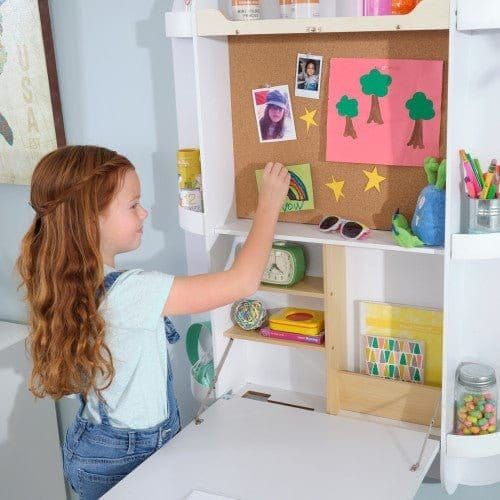girl sticking pictures to board of KidKraft Arches Floating Wall Desk & Chair - White