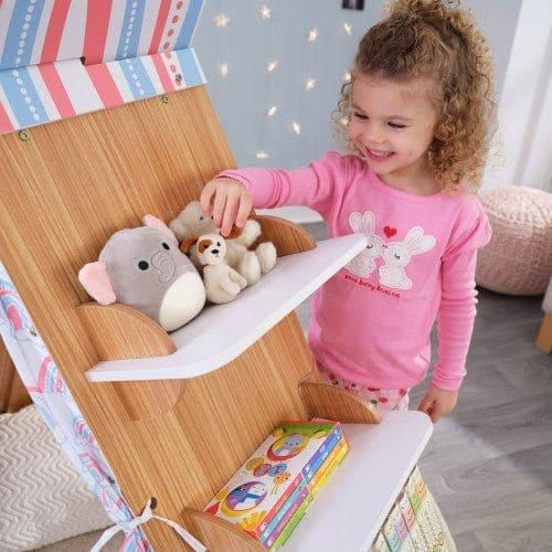 smiling girl reaching for teddy on shelf of KidKraft Book Nook Tent with Shelves