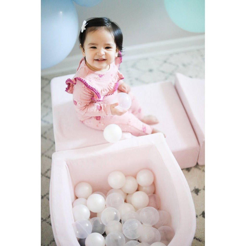 smiling girl by pale pink ball pit