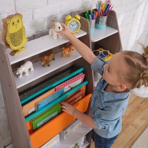 girl reaching for toy on shelf of KidKraft Pocket Storage Bookshelf - Gray Ash