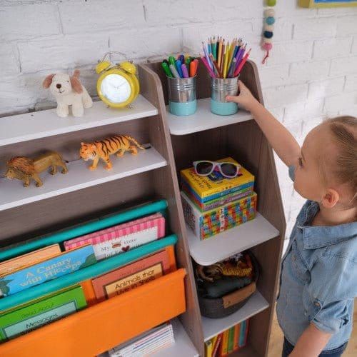 girl reaching for pen pot on top shelf of KidKraft Pocket Storage Bookshelf - Gray Ash