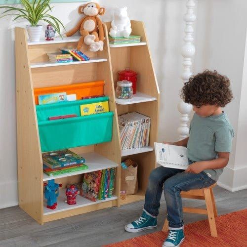boy sitting on stool in front of KidKraft Pocket Storage Bookshelf - Natural