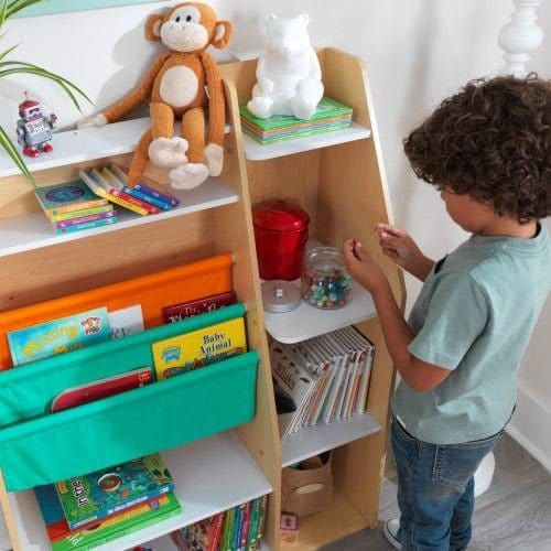 boy stood by shelf of KidKraft Pocket Storage Bookshelf - Natural
