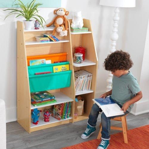 boy sitting on stool and reading book in front of KidKraft Pocket Storage Bookshelf - Natural