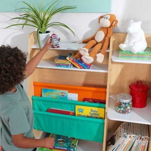 boy putting toy on shelf of KidKraft Pocket Storage Bookshelf - Natural