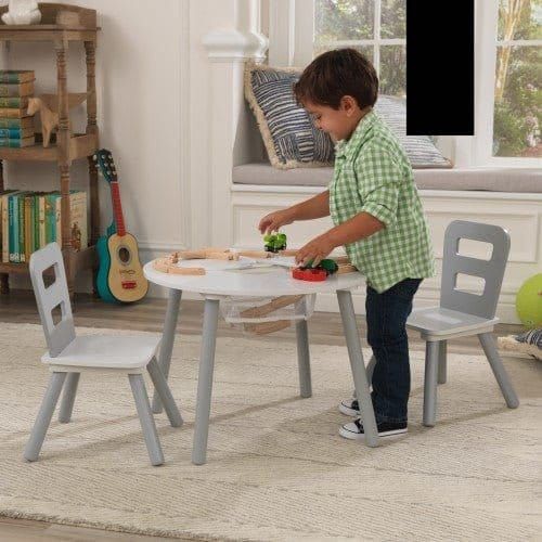 boy playing with toys in playroom with KidKraft Round Storage Table & 2 Chair Set - Grey & White