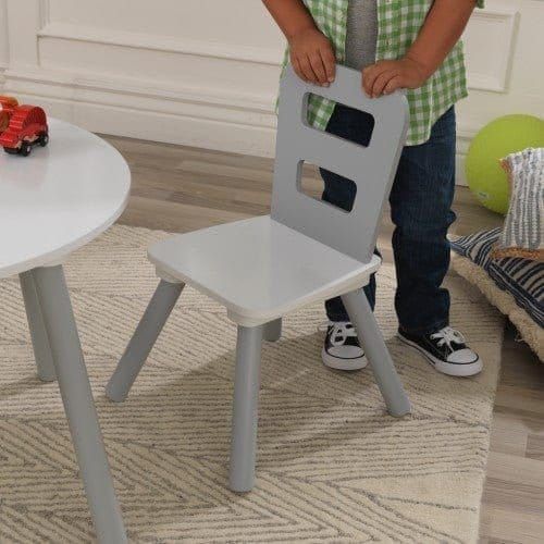 boy pulling out chair of KidKraft Round Storage Table & 2 Chair Set - Grey & White