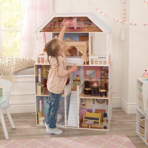 girl reaching to top floor of KidKraft Savannah Dollhouse with Furniture