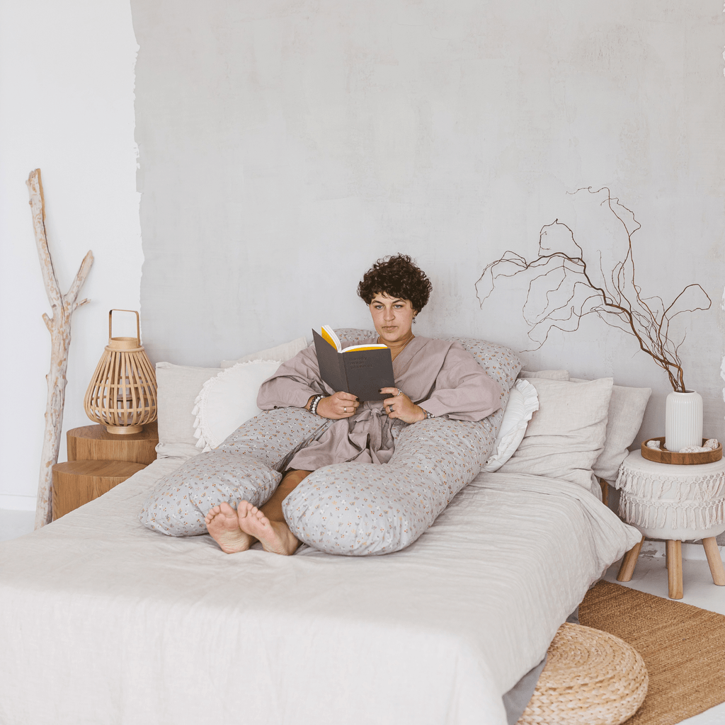 woman lying on bed reading book leaning against MINICAMP U Shape Body Pillow + Organic Cotton Cover in Grey