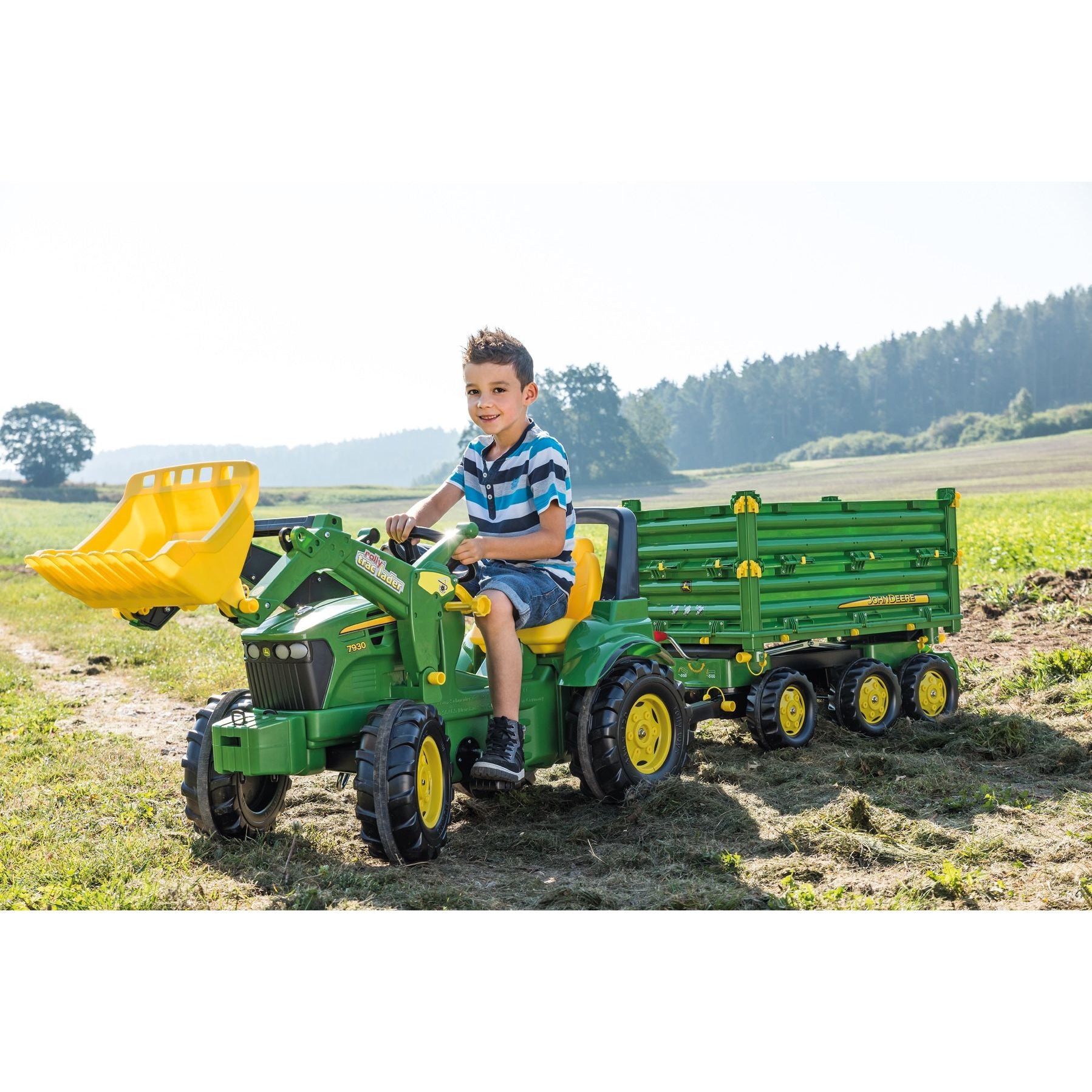 boy riding Rolly Toys John Deere 7930 Tractor With Frontloader in field