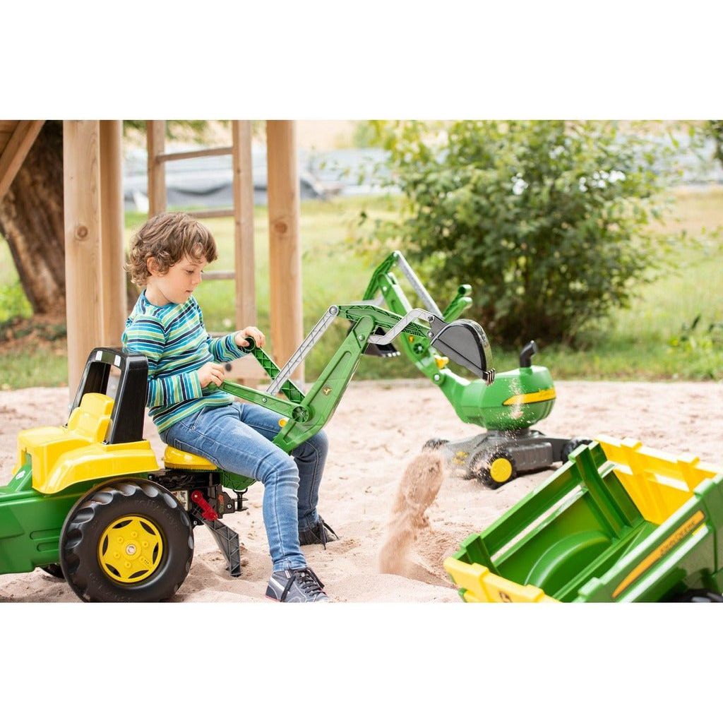 boy scooping sand in Rolly Toys John Deere Tractor With Frontloader & Rear Excavator