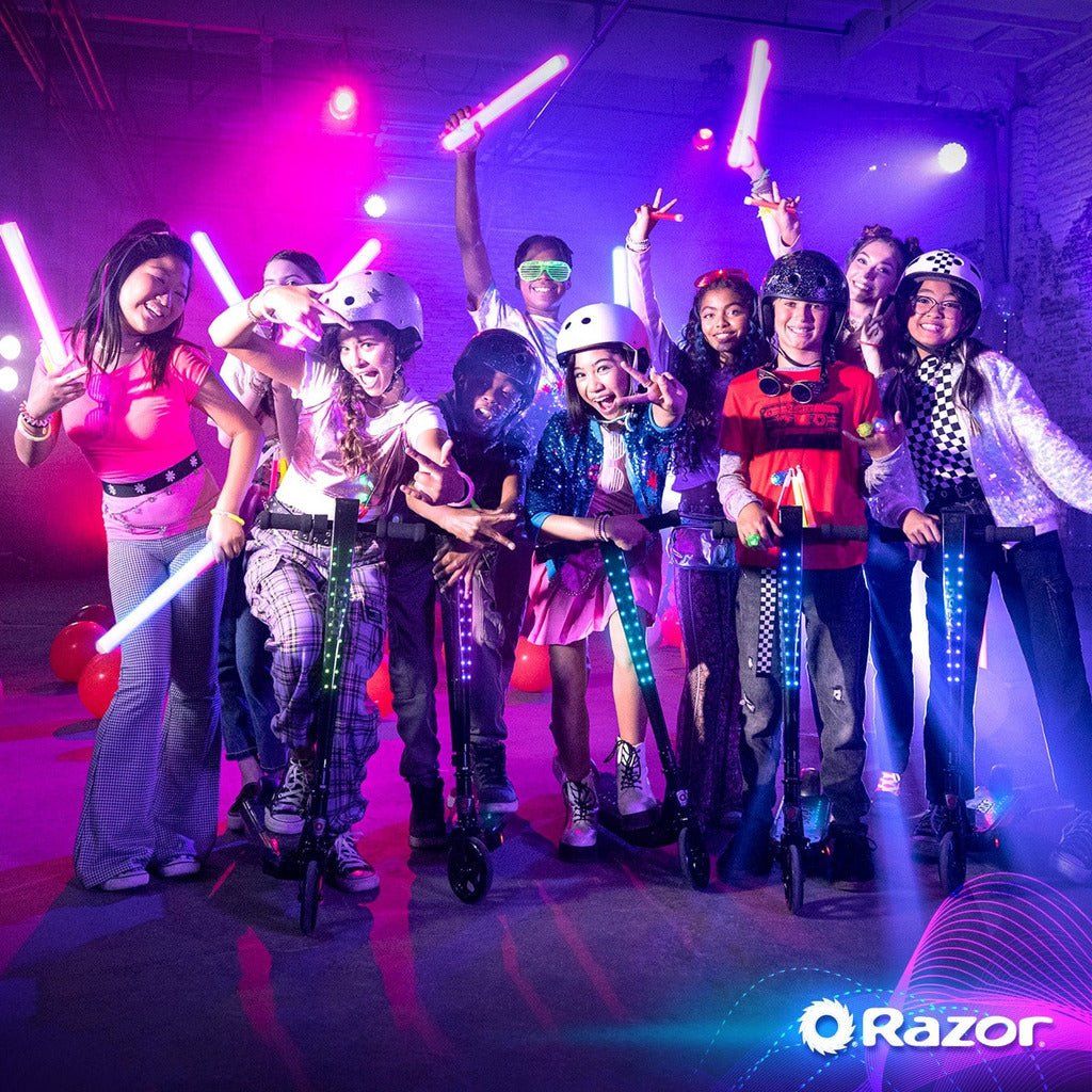 group of children with glow sticks at a party riding Razor Sonic Glow Bluetooth 24 Volt Scooters