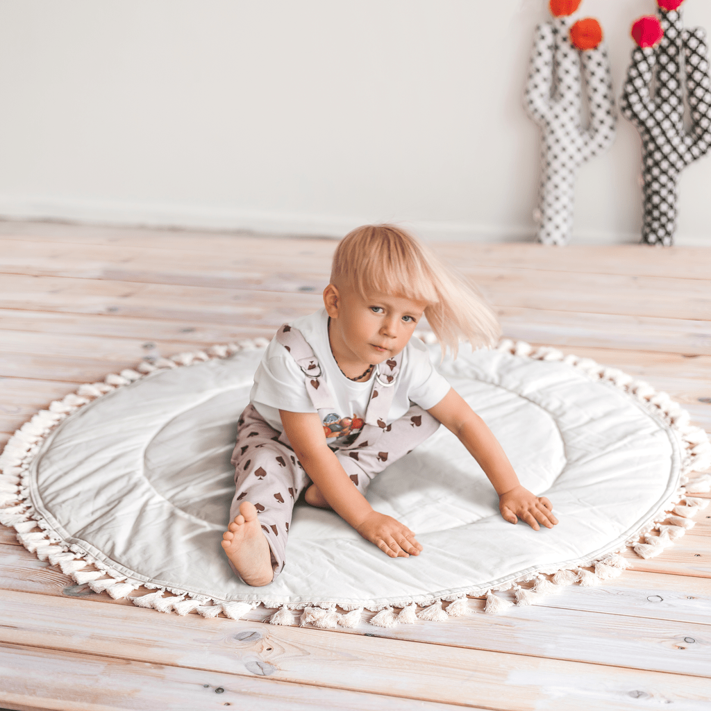 child sitting on MINICAMP Kids Playmat With Tassel Border