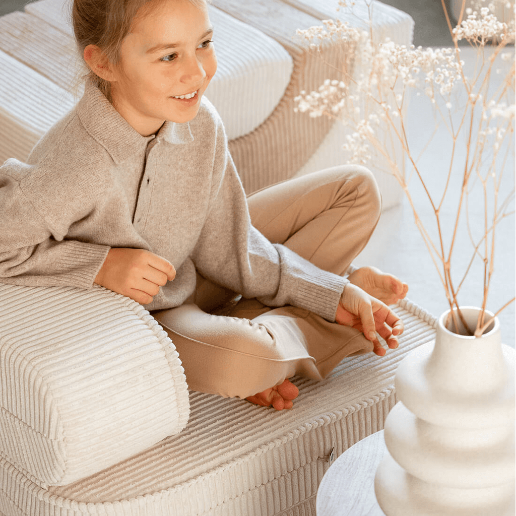 smiling girl sitting on wigiwama kids furniture Marshmallow Flip Chair