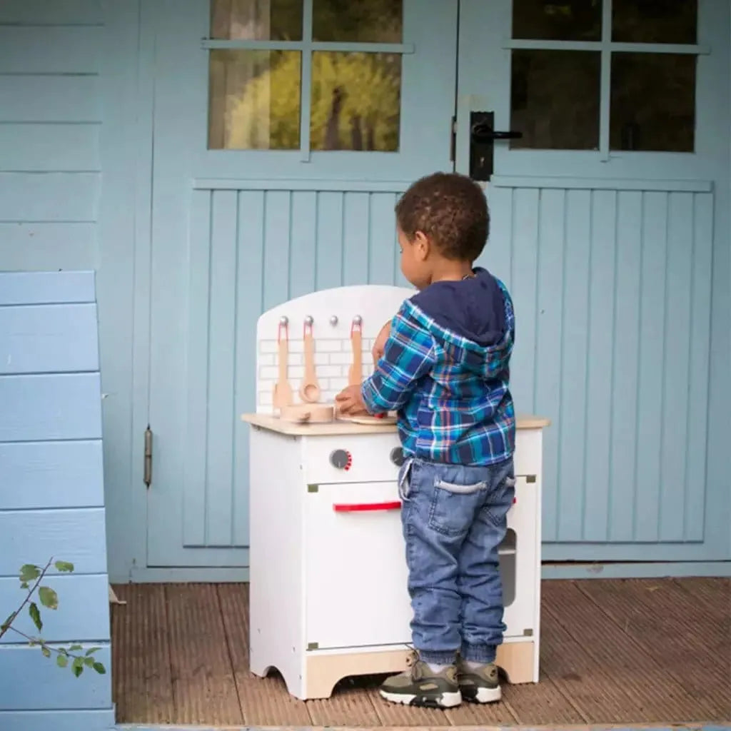 little boy standing with Classic World Wooden Chef's Kitchen Set