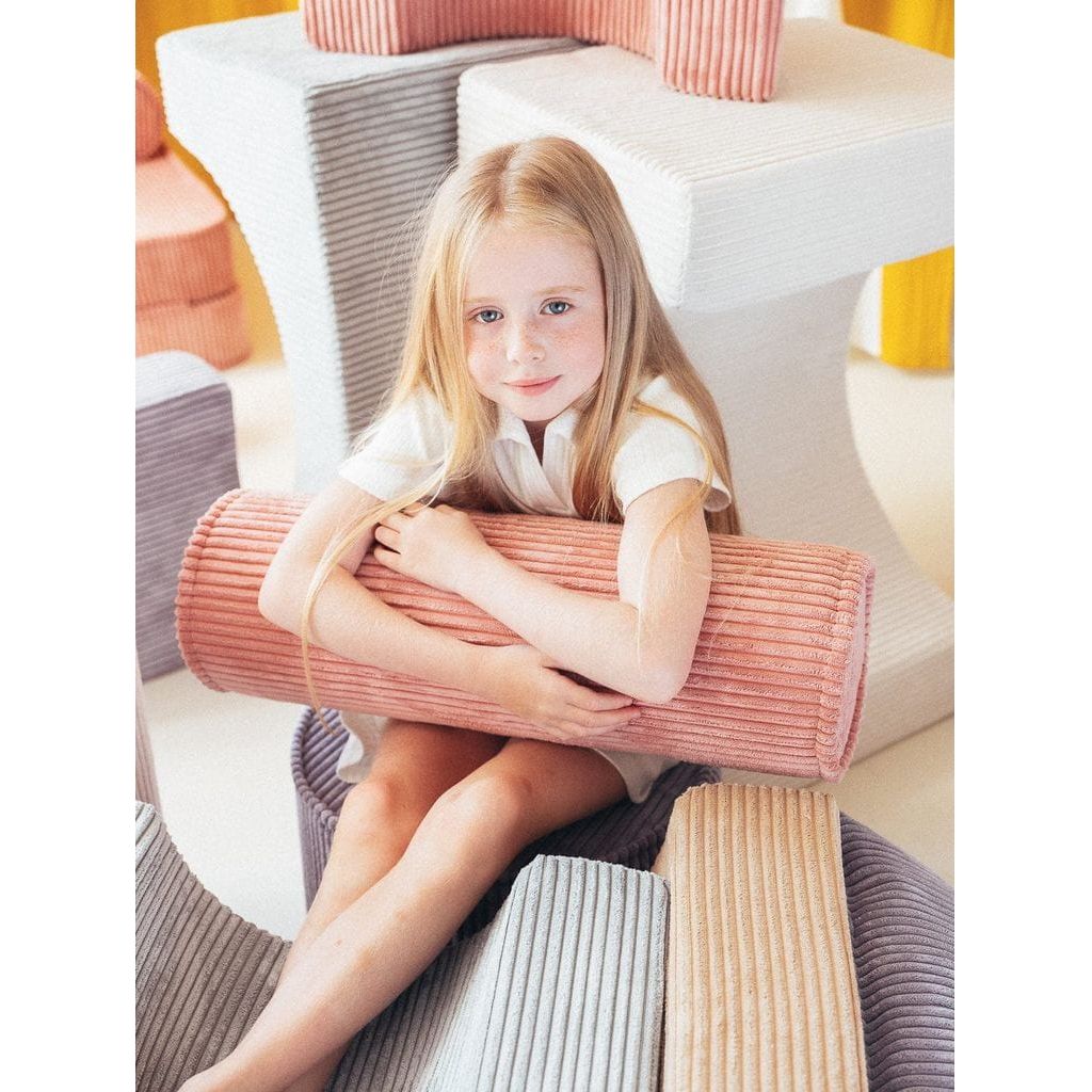 girl sitting ans holding Wigiwama Pink Mousse Roll Cushion