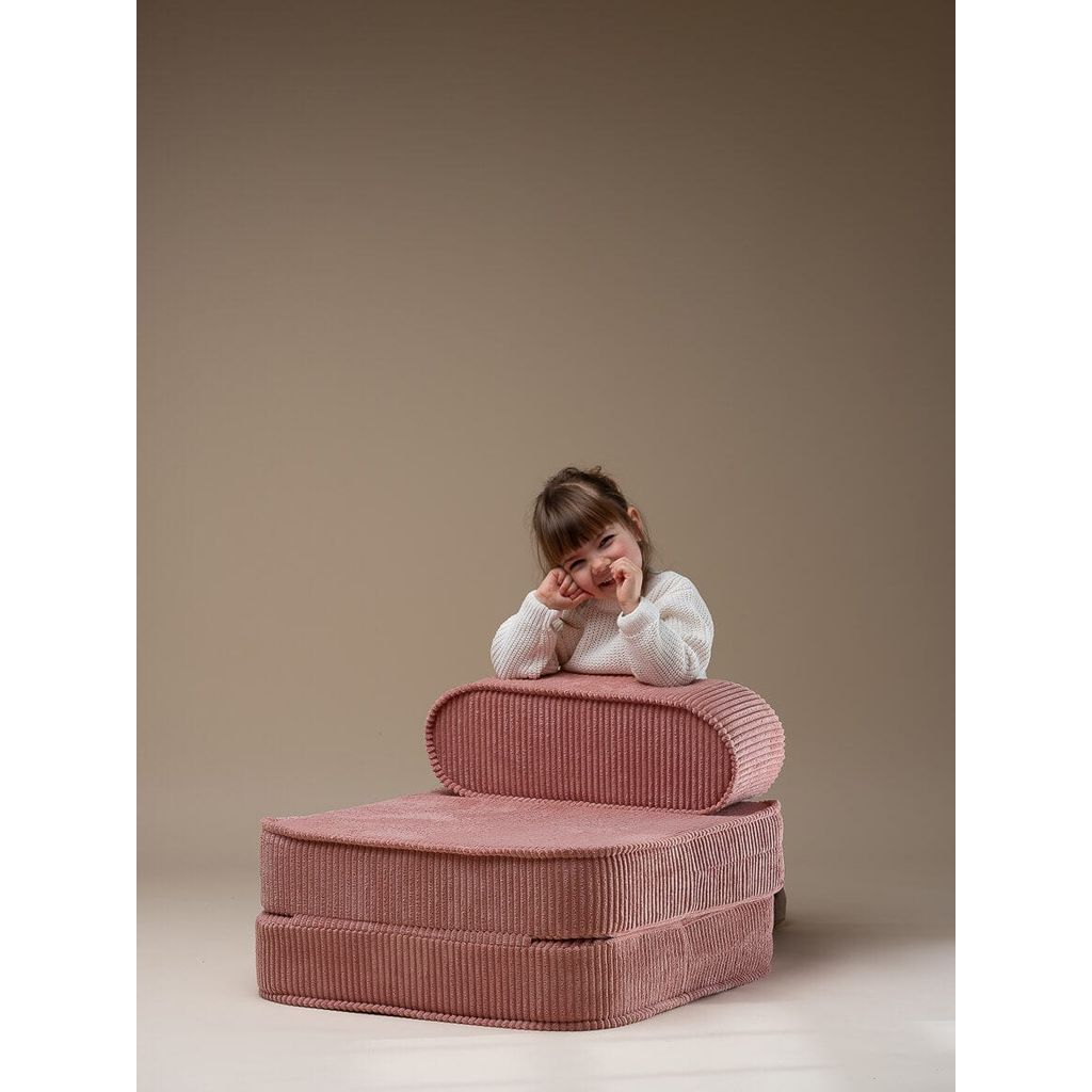 girl leaning on back of Wigiwama Pink Mousse Kids Flip Chair