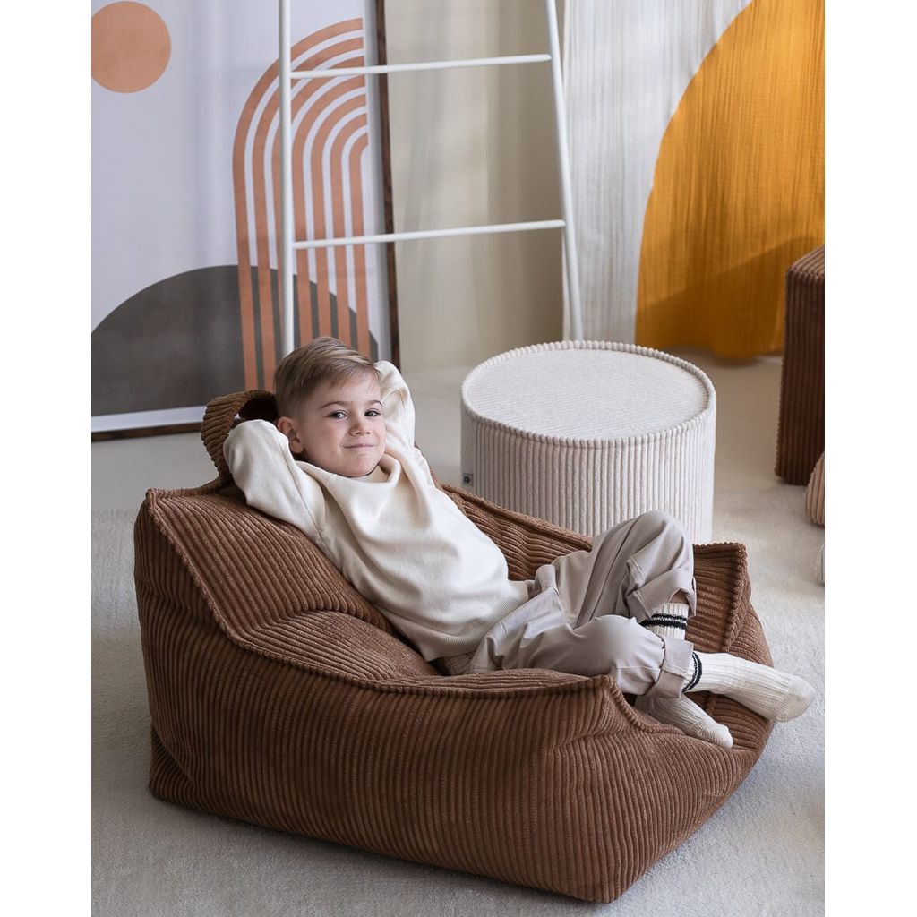 boy with arms behind head sitting on Wigiwama beanbag chair and Marshmallow Pouffe kids furniture