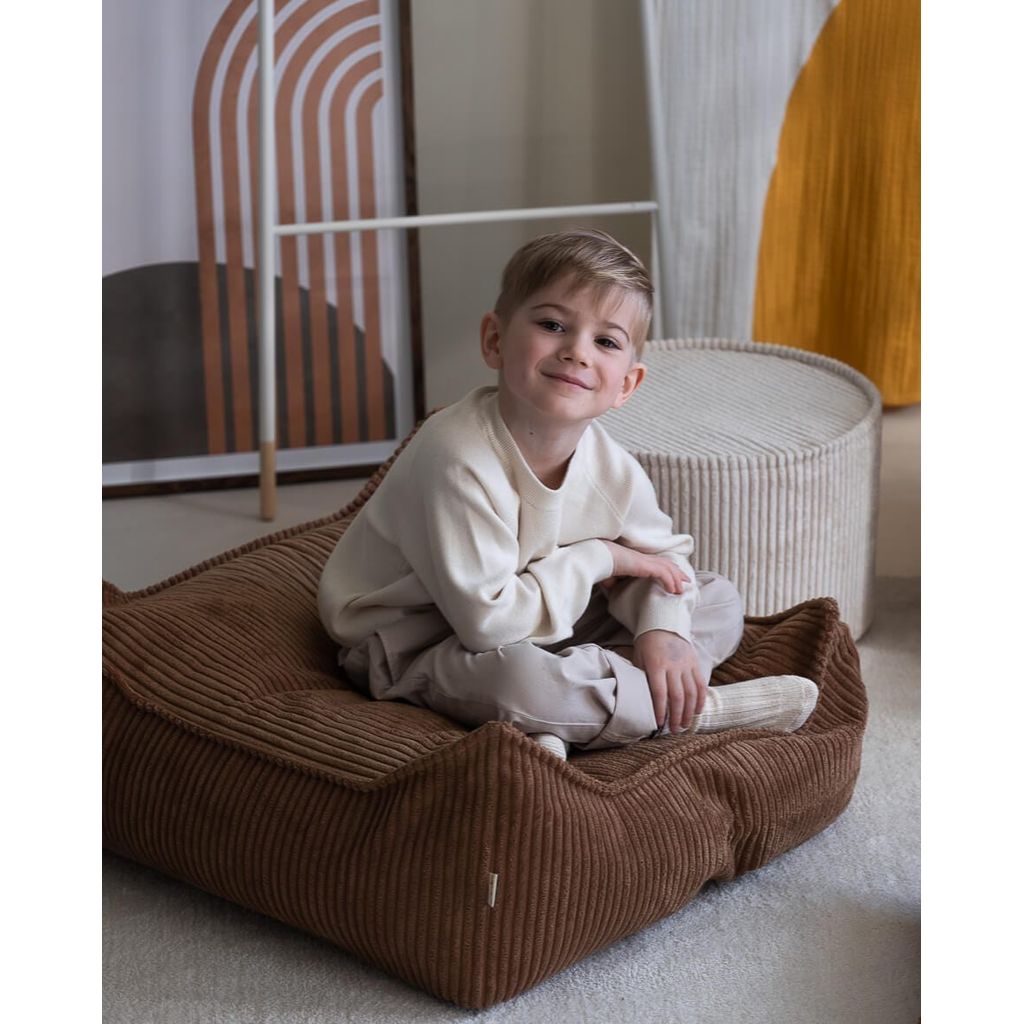 boy sitting cross legged on Wigiwama Toffee Square Ottoman kids furniture