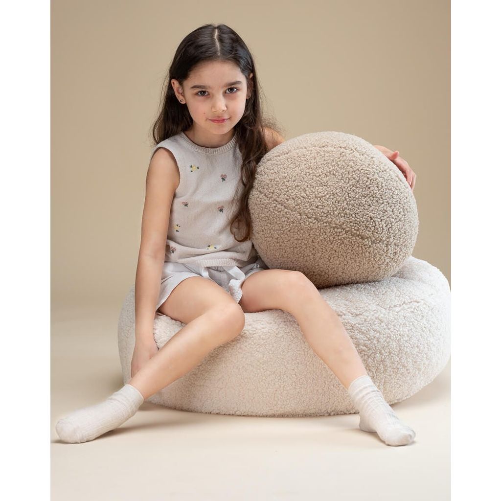 girl sitting on Wigiwama Cream White Ottoman and holding ball cushion