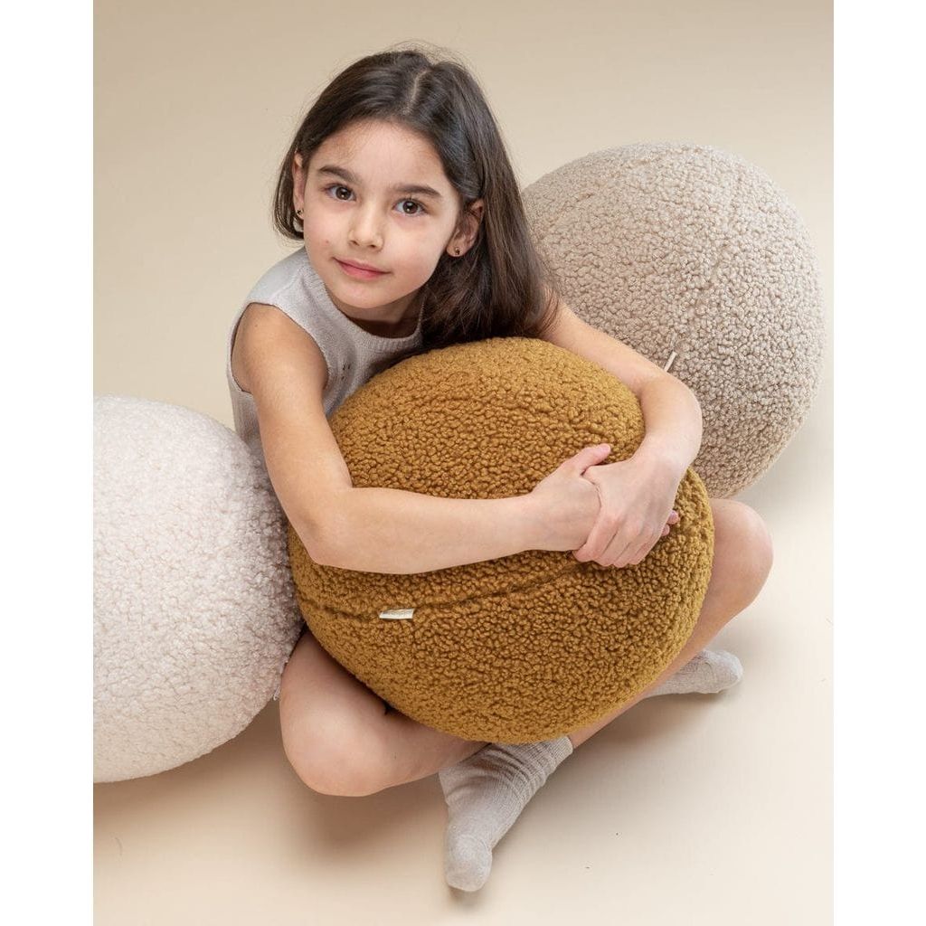 girl sitting cross legged holding Wigiwama Cream White Ball Cushion