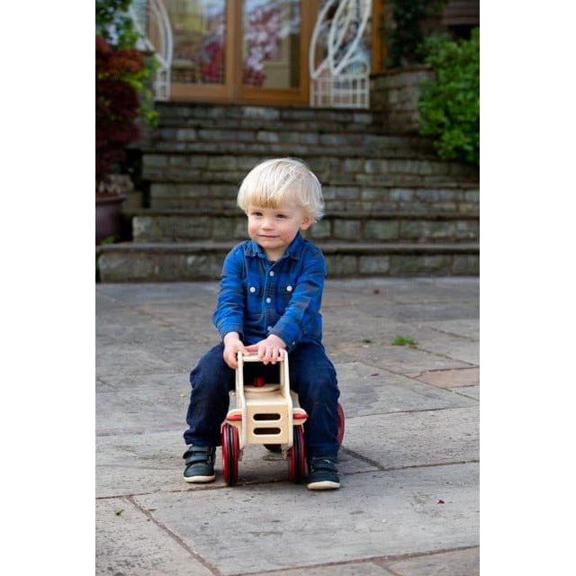 blonde boy sitting on Moover dump truck ride on in natural wood colour