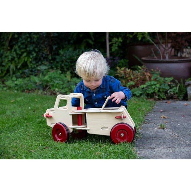 little boy playing in garden with Moover dump truck ride on in natural wood colour