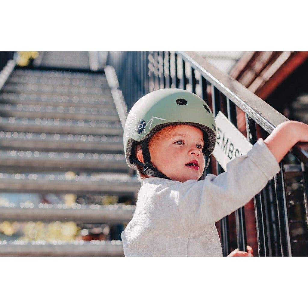 little boy  holding handrail and wearing Scoot and Ride Helmet - XXS - S - Green Lines