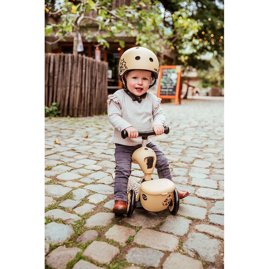 boy sitting on Scoot and Ride Highwaykick 1 Lifestyle Scooter - Leopard while wearing helmet