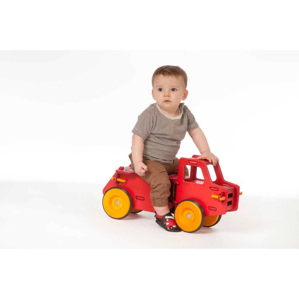 little boy sat on red moover wooden cump truck