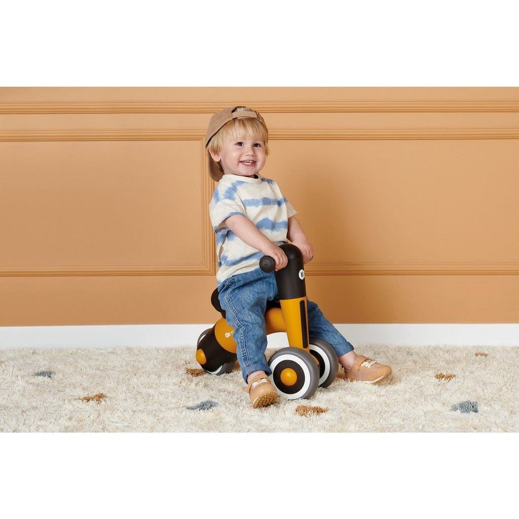 boy sitting on Yellow Kinderkraft Minibi Tricycle